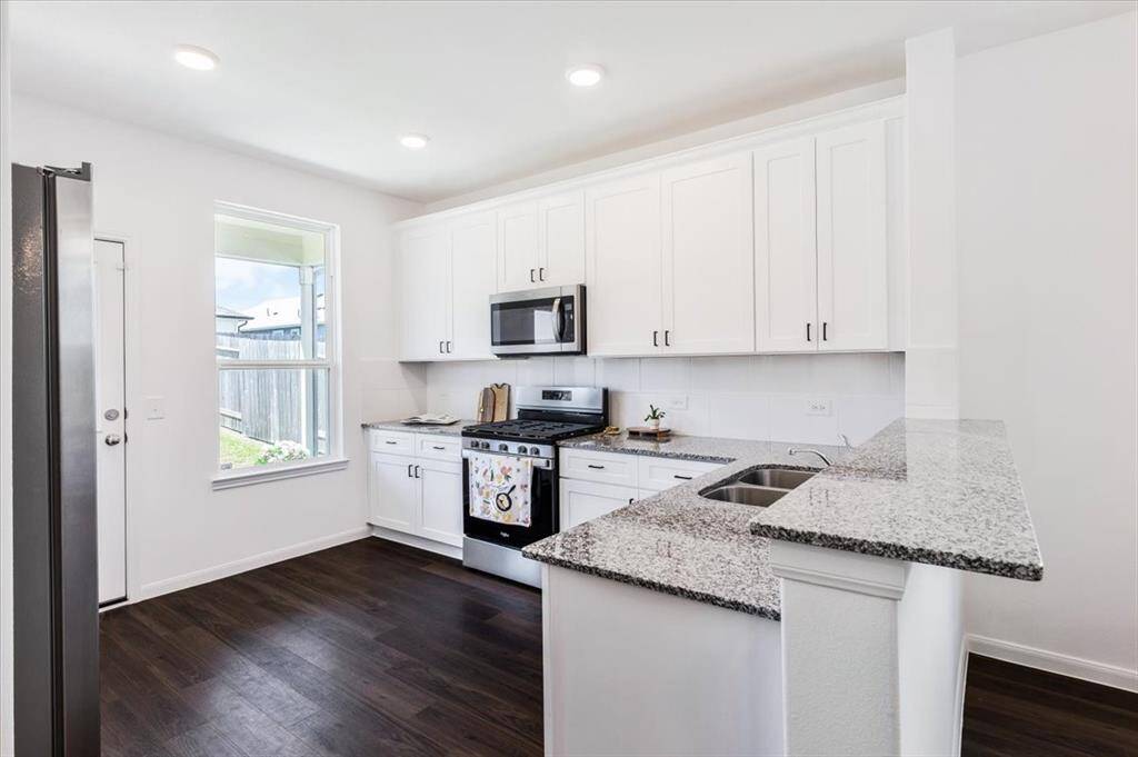Kitchen features granite countertops , beautiful white cabinets with updates hardware, stainless appliances, large sink and natural light.