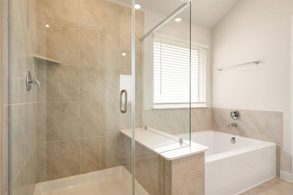 This additional view of the primary bath showcases a walk-in shower with tile surround and a separate garden tub perfect for soaking after a long day.