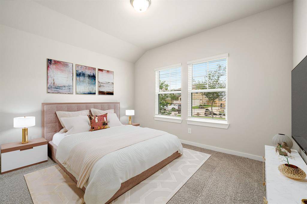 This bright and inviting bedroom features plush carpeting, high ceilings, and large windows that flood the space with natural light. The neutral color palette offers a blank canvas, perfect for any style, while the clean lines and modern finishes create a fresh, comfortable atmosphere.