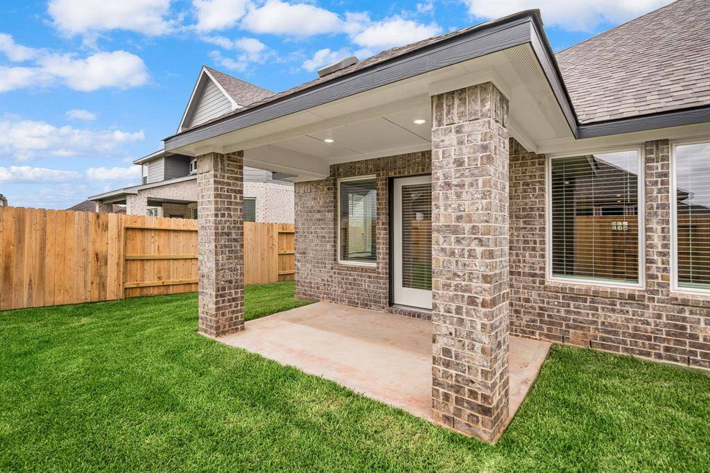 Step into outdoor comfort with this charming covered patio, perfect for relaxing or entertaining. Featuring sturdy brick columns, recessed lighting, and a spacious concrete slab, this backyard retreat offers privacy with a fully fenced yard and lush green grass. Ideal for enjoying sunny afternoons or cozy evenings right outside your door.