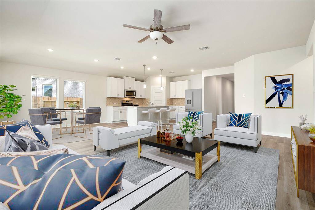 This bright and open-concept living space features a seamless flow between the kitchen, dining, and family areas. With abundant natural light, recessed lighting, and stylish finishes including white cabinetry, stainless steel appliances, and a spacious island with bar seating, this space is perfect for everyday living and entertaining.