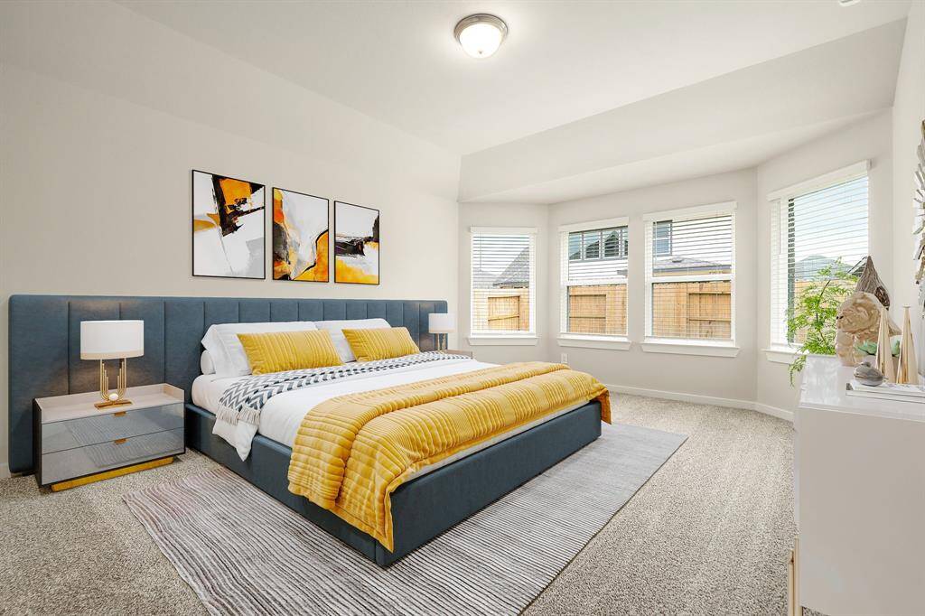 This spacious primary bedroom offers a serene retreat with plush carpeting, soft neutral tones, and an elegant tray ceiling. A wall of large windows invites an abundance of natural light, creating a bright and airy atmosphere with views of the backyard for added privacy and comfort.