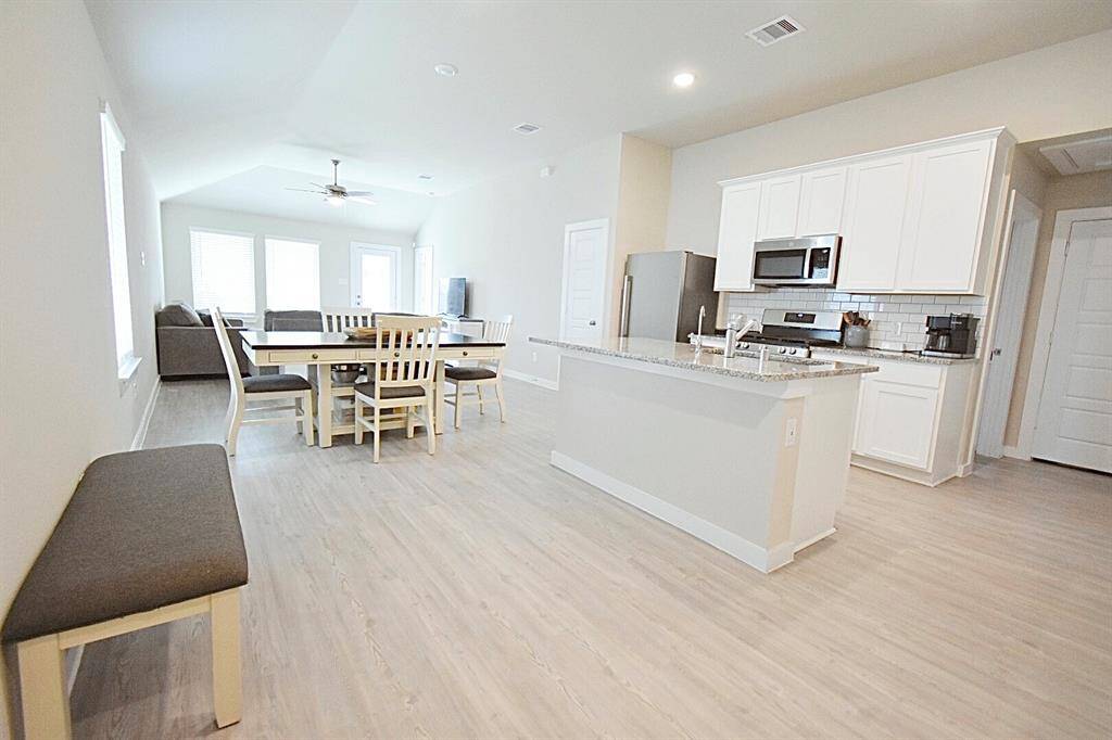 As you enter the home, you are greeted by an open kitchen, dining area, and beautiful light neutral grey vinyl plank flooring.