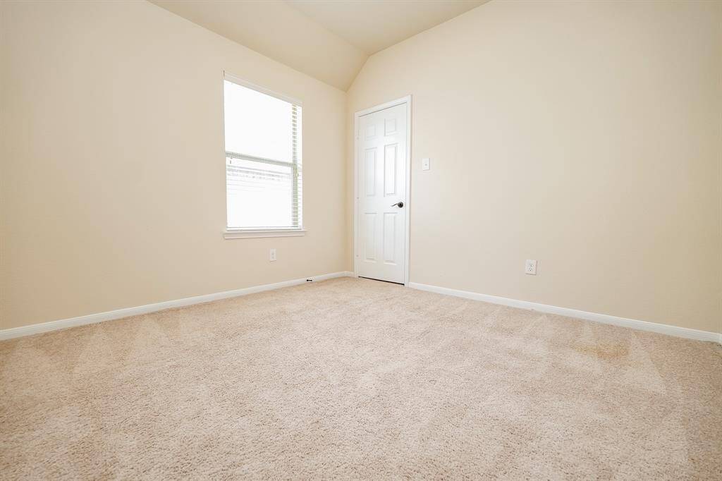 A corner window in a carpeted secondary bedroom offers more wall/floor space for furnishings.