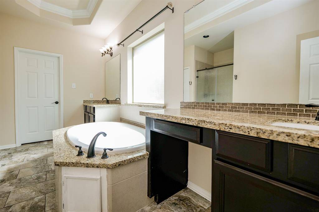 Contemporary simplicity is the key to casual elegance in your primary ensuite bath; with warm tray ceiling, soothing walls and beautiful tile flooring; dual/separate sinks/vanity set into striking caramel colored granite counter tops, with rich dark cabinetry below and simple wall-wide mirrors, above. The huge frosted glass window makes bathing completely private!