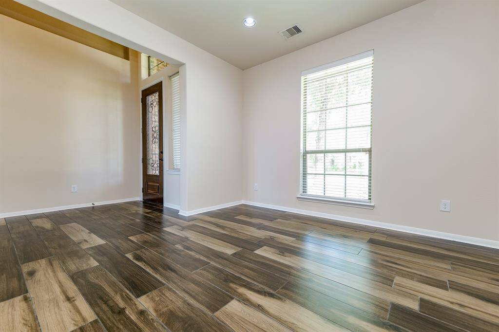 Dynamic wood-look tile (throughout the 1st floor) hosts a high ceiling in this bright front room, right off the main entry foyer. This brilliant space is perfect as a home office/study or for anything your lifestyle needs/wants.