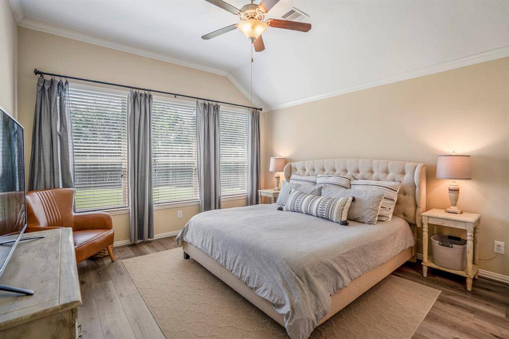 Primary Bedroom with a vaulted ceiling, crown molding, a ceiling fan and views of the backyard