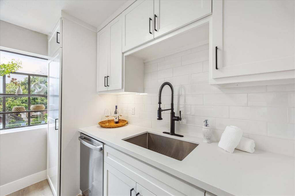 Large basin sink and stylish water faucet.  Note the lovely garden window to the left.  Stacked washer and dryer are in the tall cabinet next to the window.