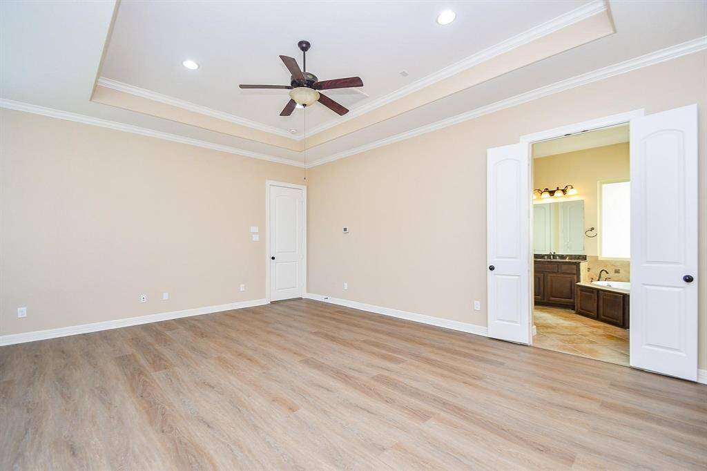 This kitchen features elegant dark wood cabinetry, granite countertops, and a stylish tile backsplash. It includes modern stainless steel double ovens and a gas cooktop, set on a spacious layout with ample storage.