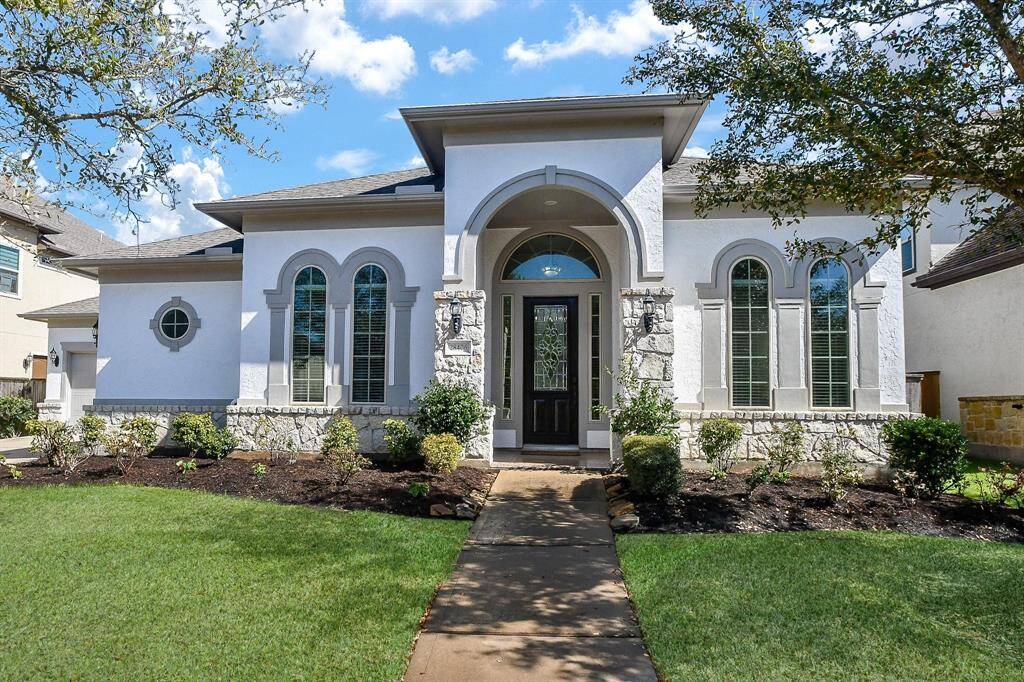 This photo showcases a charming, single-story home with a modern facade, featuring arched windows and a welcoming front entry. The well-maintained landscaping and lush lawn add to its curb appeal.