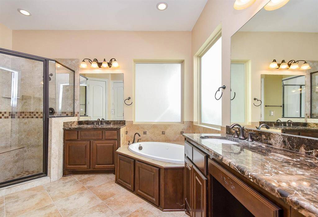 This bathroom features a clean, modern design with a granite countertop, undermount sink, and elegant dark wood cabinetry. It includes a tiled shower area, a window for natural light, and neutral-toned walls for a warm ambiance.