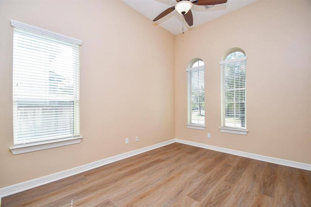 This spacious bathroom features a luxurious corner bathtub, dual sinks with marble countertops, and a large glass-enclosed shower. Warm lighting and wood cabinetry add a touch of elegance.