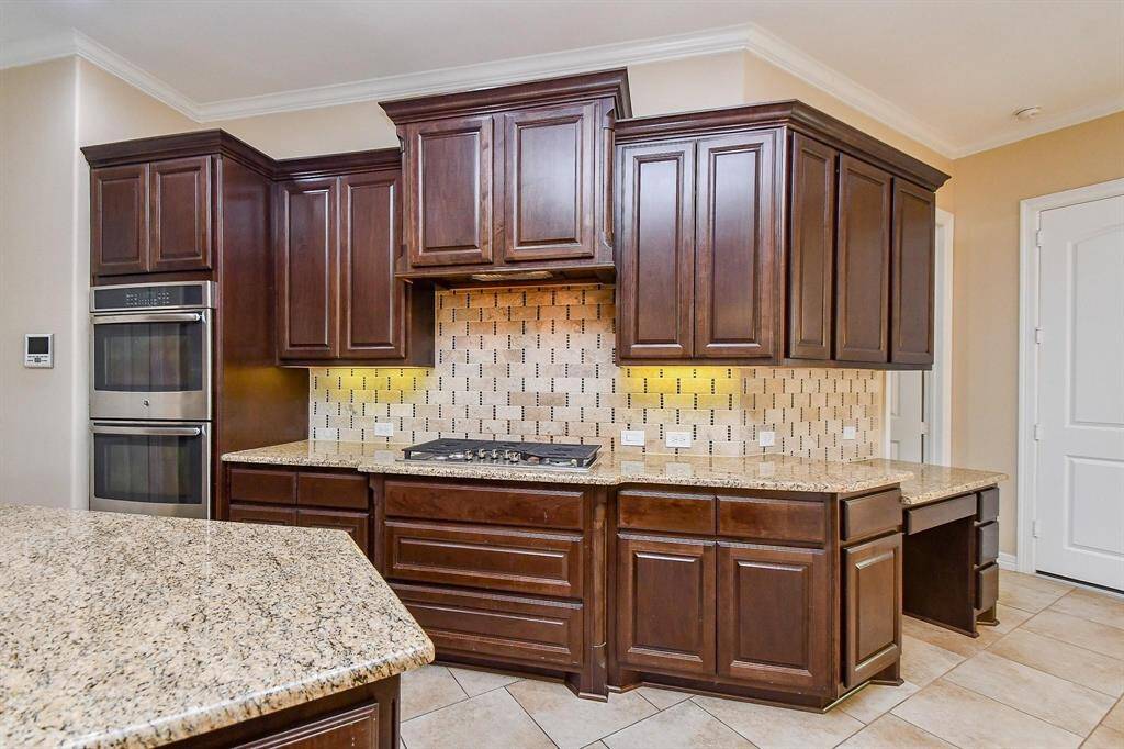 This spacious kitchen features elegant dark wood cabinetry, granite countertops, and modern stainless steel appliances. The open layout provides ample space for cooking and entertaining, with stylish tile flooring and recessed lighting.