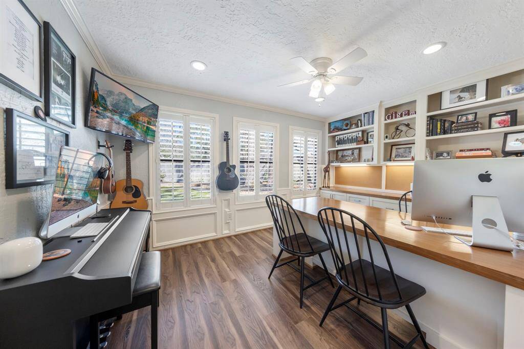 Off the family room, near the stairwell, is a dedicated study featuring custom millwork, plantation shutters with backyard views, and a built-in desk, shelving, and storage.
