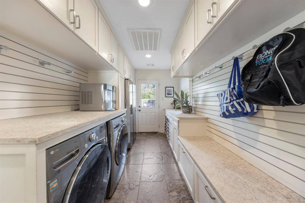 Through the kitchen, you'll enter the mudroom, complete with custom built-ins for the washer, dryer, refrigerator, and ample storage. This space offers access to the backyard, front yard, garage, powder bath, and an additional stairwell.