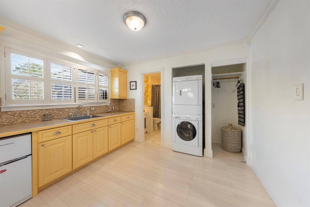 The kitchenette is fully equipped with a mini fridge, sink, countertop space, cabinetry, room for a stacked washer and dryer, and additional closet/storage space.