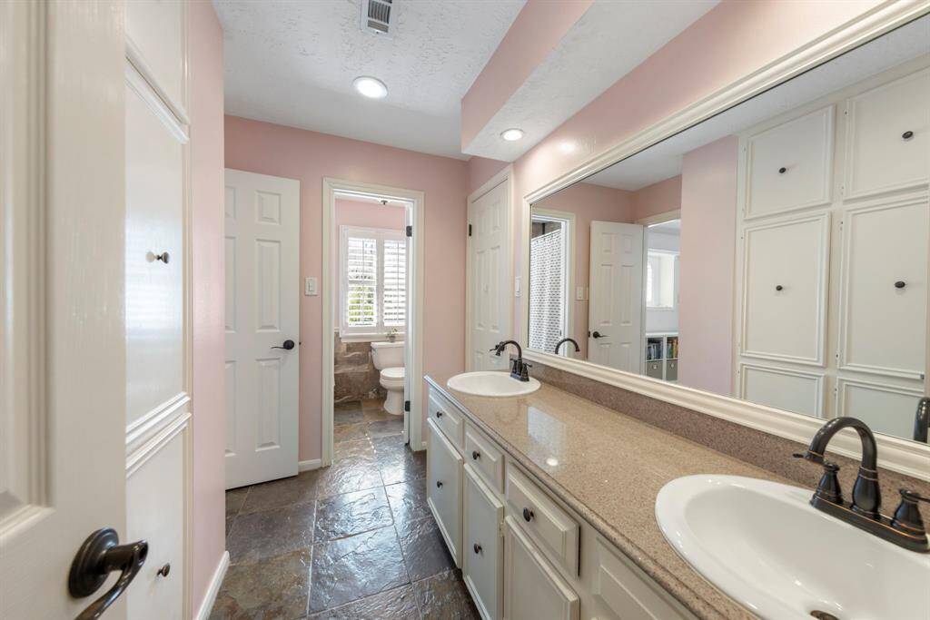 The Jack-and-Jill bathroom features tile flooring, ample storage, and a shower/tub combo for convenience.