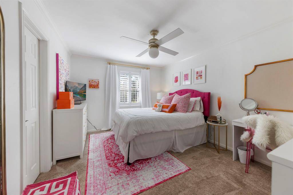 The third upstairs bedroom features plush carpet, a ceiling fan, a walk-in closet, and plenty of natural light from the windows.