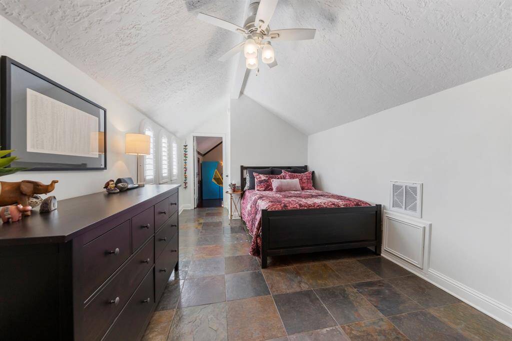 The fourth and final upstairs bedroom boasts tile flooring, a ceiling fan, windows for natural light, an en-suite bathroom, and direct access to the game room.