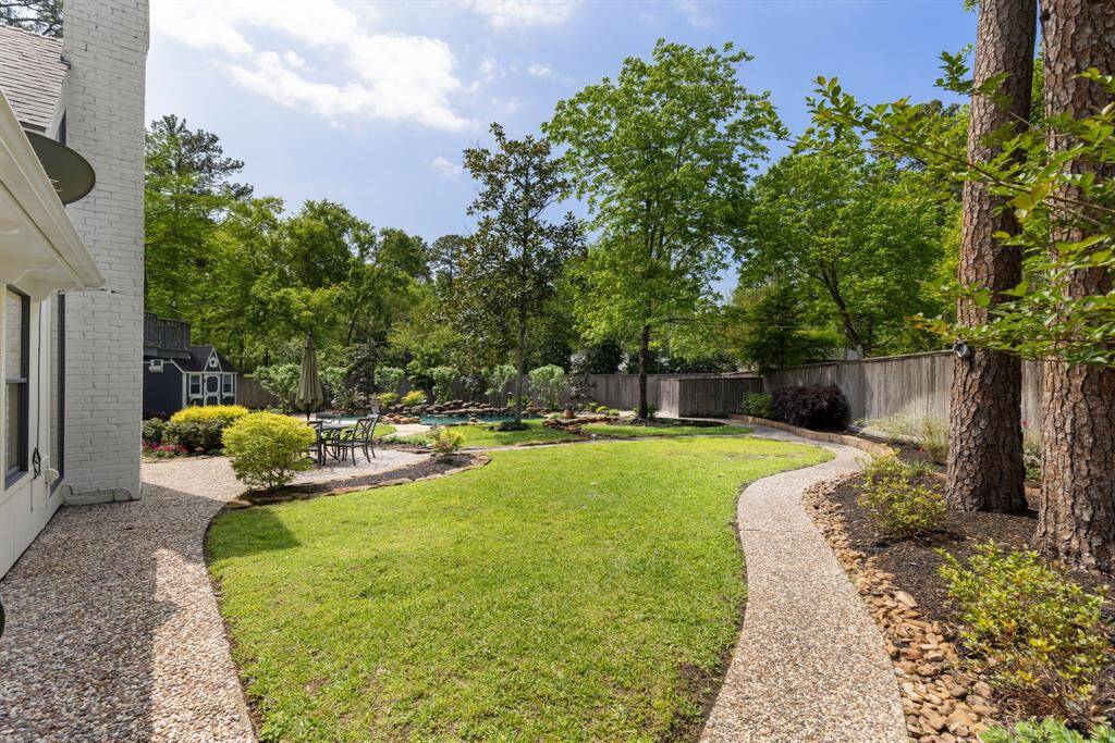 The spacious backyard features plenty of green space, with walking paths that surround the property, all complemented by lush landscaping.