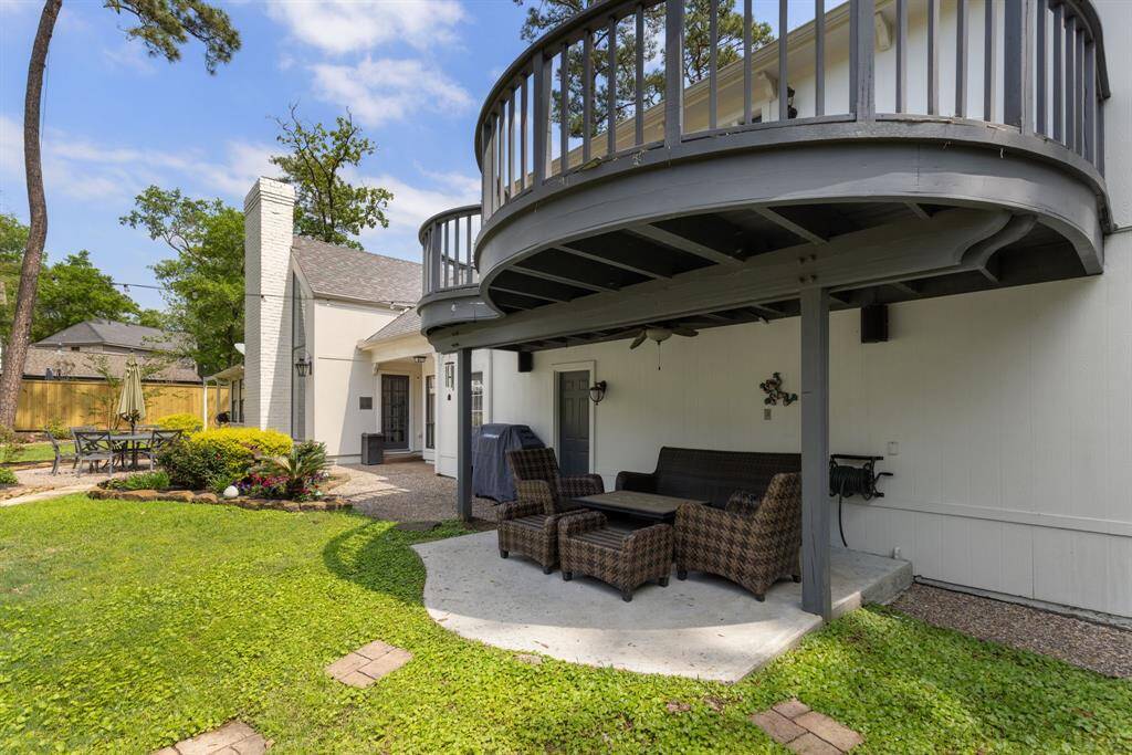 Beneath the balcony is a covered seating area, ideal for enjoying the outdoors in comfort and shade.