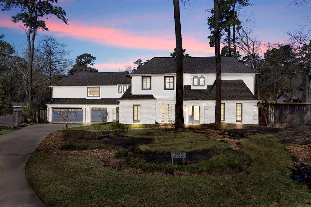 A stunning white painted brick exterior, a long driveway leading to a spacious 3-car garage, and lush landscaping create a beautiful first impression.