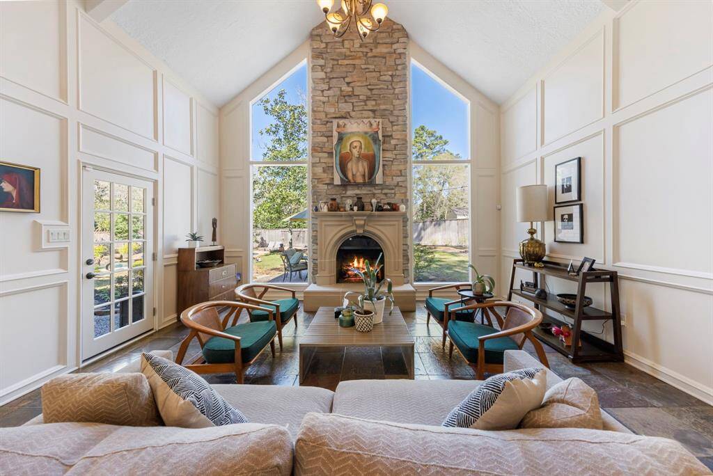 Custom millwork and a striking stone fireplace are beautifully flanked by floor-to-ceiling windows, creating a stunning focal point in the room.