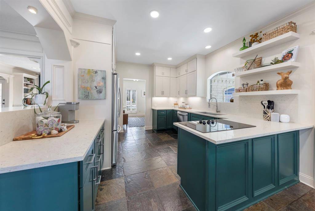 Off the family room is the updated, functional kitchen featuring Vicostone Akoya countertops, custom-painted cabinetry, and stylish open shelving.