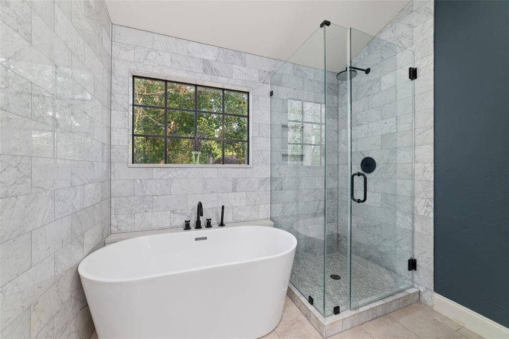 Tub and shower are wrapped in timeless floor-to-ceiling Carrara tile.