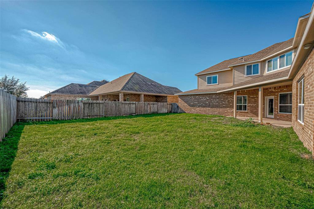 Has an inviting backyard, showcasing a beautiful grassy area and a stylish fence ideal for outdoor living and entertaining.