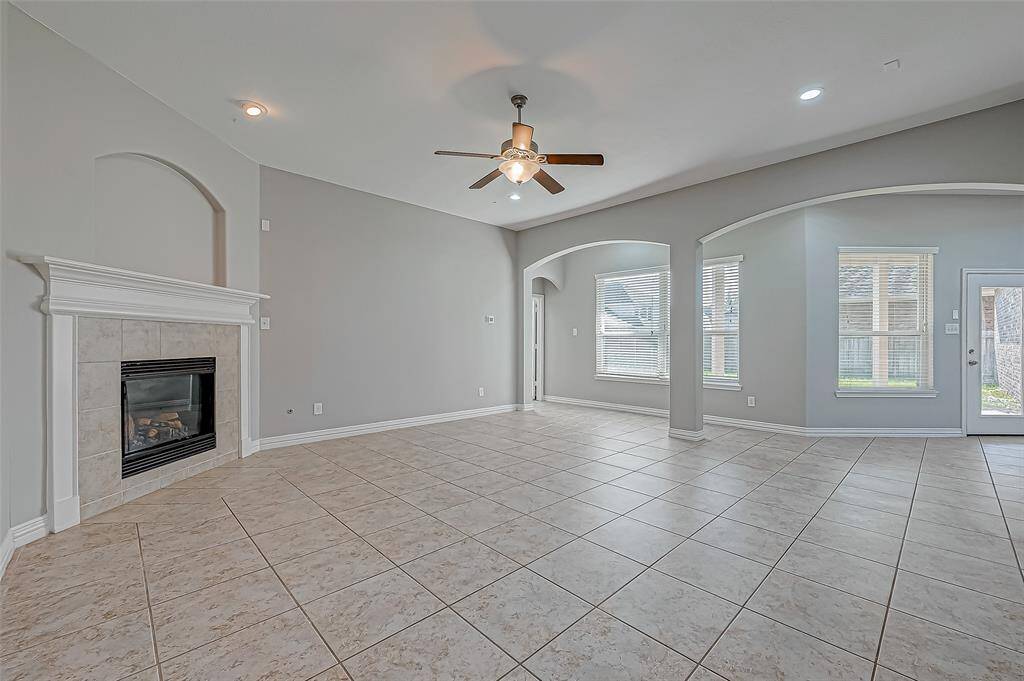 Bright, open living room with tile flooring and a ceiling fan, perfect for your family's relaxation and entertainment.