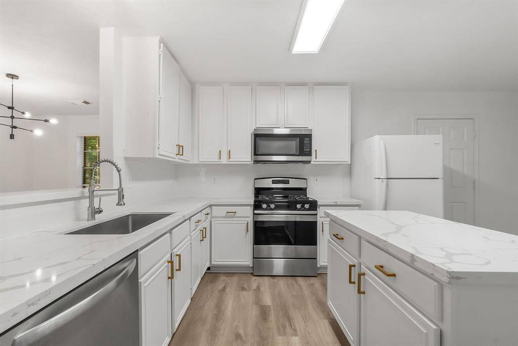 Enjoy Quartz countertops, sparkling undermount sink, painted cabinetry with updated hardware and gorgeous black and gold fixtures in the kitchen.