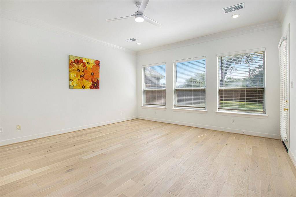 This is the primary bedroom, which features wood floors, 3 large windows with blinds, and a very modern ceiling fan.