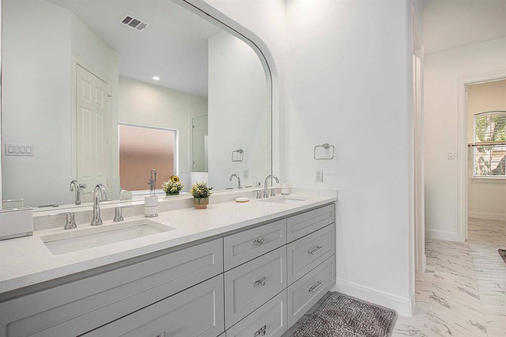 The master bath has been totally remodeled! Double sinks with new fixtures, a double vanity featuring sleek gray cabinets and a large mirror.