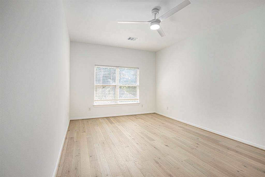 This is a bright, spacious room featuring light wood flooring and a ceiling fan, with a window providing ample natural light. Perfect for a bedroom or second office space.
