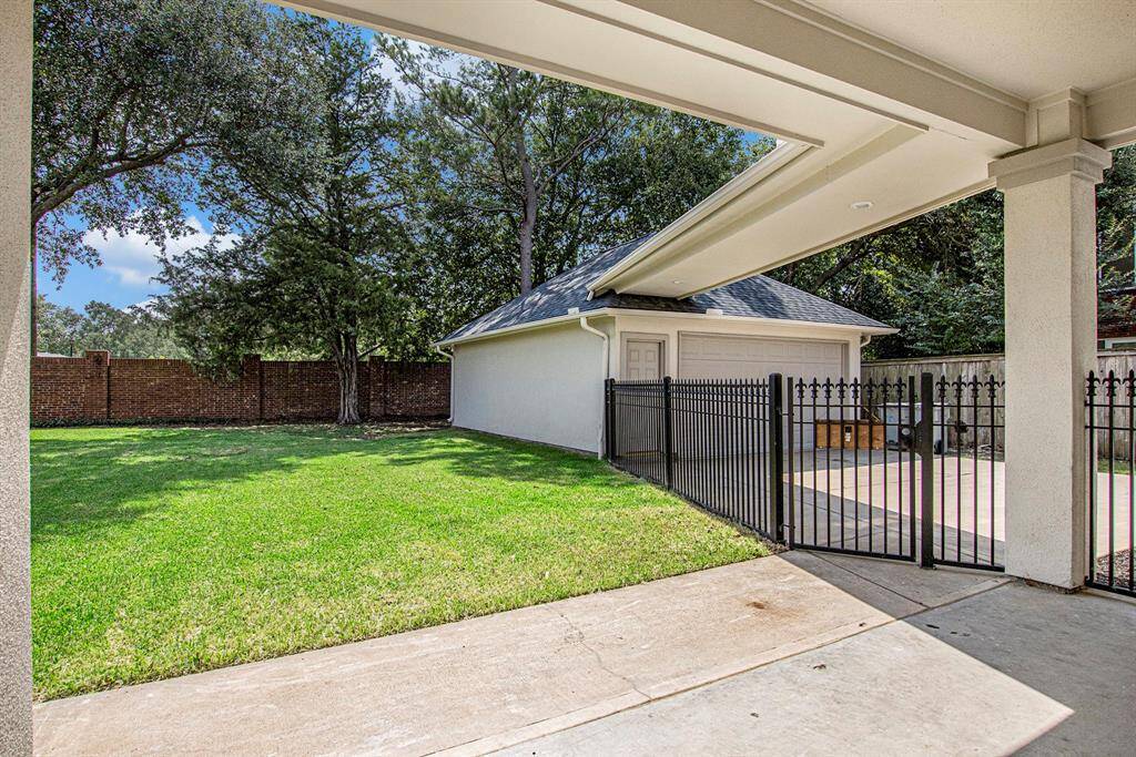 Spacious backyard with a well-maintained lawn, shaded by mature trees. Features a detached garage with a gate to keep pets in. Perfect for outdoor activities