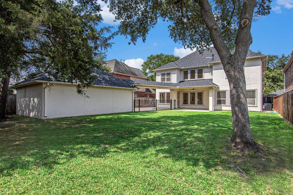 This photo showcases a spacious backyard with a lush lawn and mature trees. Notice the covered patio, accessible by two separate doors. Add a pool or playset to the backyard, or just leave it wide open!