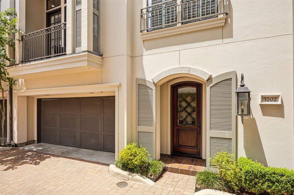 This inviting entryway features a covered porch with classic gas coach lighting, elegant cast stone trim around the windows, and decorative shutters. The 8-foot front door, newly sanded, sealed, and stained in 2025, adds a bold and sophisticated touch.