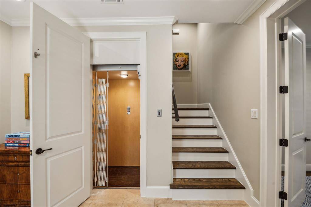 This home features an elevator servicing all three floors, upgraded with a high-performance XIS Speedmaster system in 2021. The staircase is accented with decorative iron railings and rich wood treads, blending functionality with timeless style.