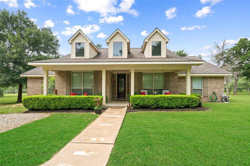 Charming curb appeal with a classic brick façade, manicured landscaping, and a welcoming covered front porch ideal for relaxing with a view.