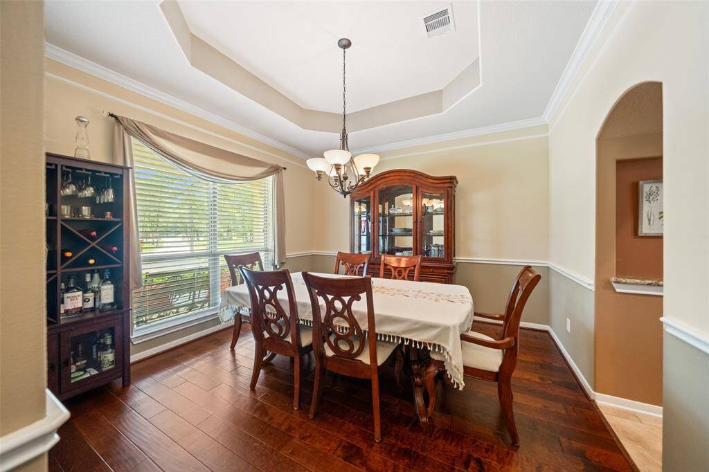 Well-lit dining room with a tray ceiling and elegant wood trim, perfect for entertaining or enjoying intimate family meals.