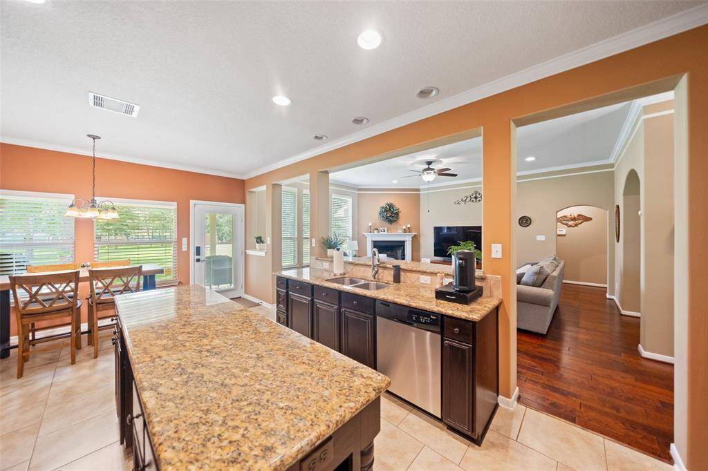 A wide layout seamlessly connects the kitchen to the living room, with bar seating, ample cabinetry, and a convenient pass-through design.