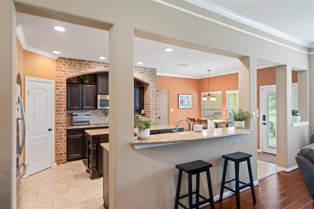 View into the spacious kitchen showcasing granite counters, bar seating, and open access to the breakfast nook and backyard.
