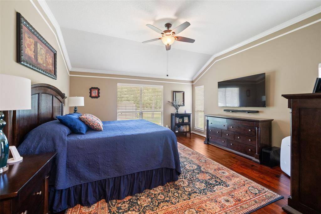 Natural light streams through multiple windows in this well-appointed bedroom, complete with a ceiling fan and views of the serene backyard.