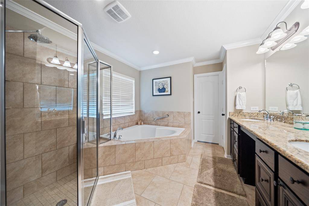 The spacious primary bath offers a luxurious soaking tub, walk-in shower, and granite-topped dual vanities—designed for everyday comfort and ease.