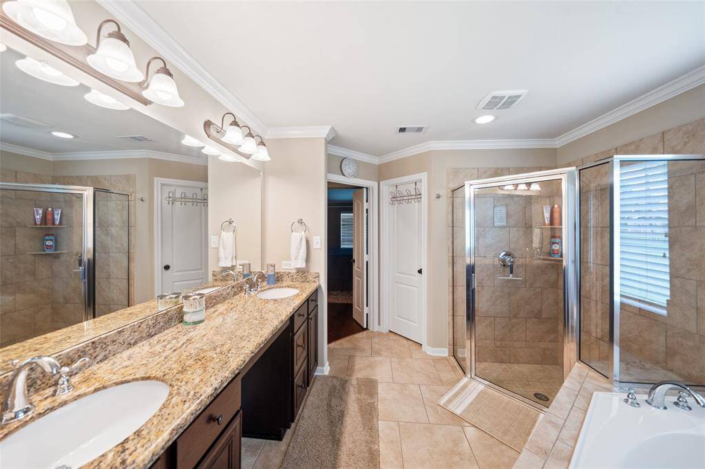 Another angle highlights the generous layout, featuring rich cabinetry, framed mirrors, and a seamless blend of tile and granite finishes.