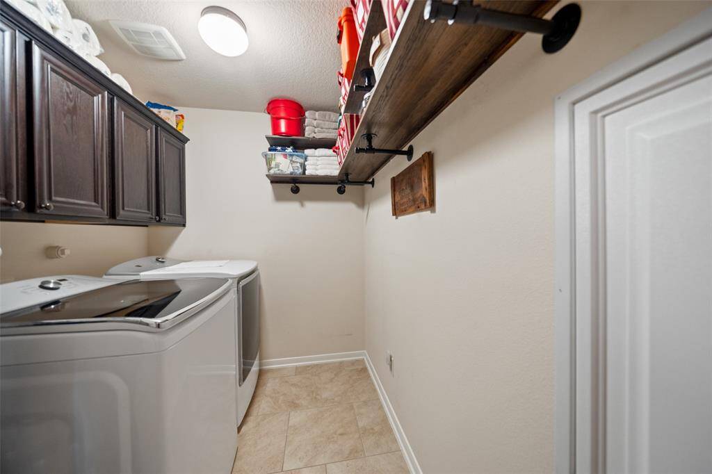 Efficient laundry space with upper cabinets and rustic-style shelving, offering practical storage and a tidy layout.