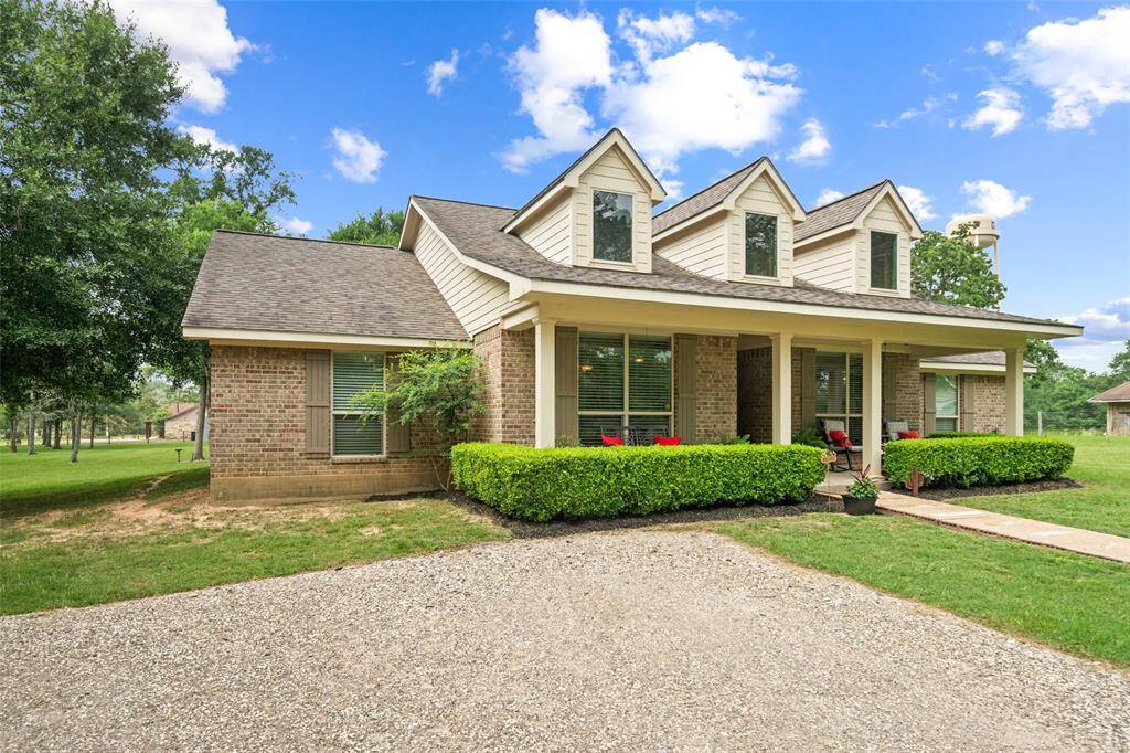 Charming curb appeal with brick and siding exterior, a welcoming covered porch, and manicured landscaping.