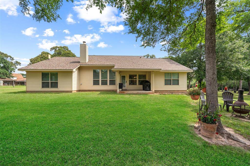 Rear elevation of the home highlights the covered patio and abundant windows overlooking the lush backyard.