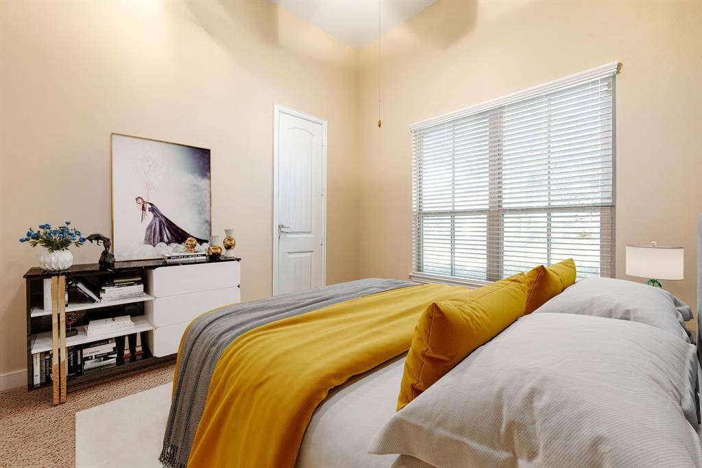 Secondary bedroom features plush carpet, custom paint, dark stained ceiling fan with lighting and a large window with privacy blinds. *virtual staging*